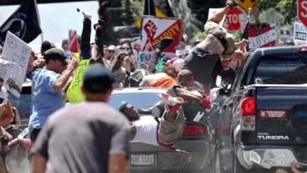 FILE - In this Aug. 12, 2017, file photo, people fly into the air as a vehicle drives into a group of protesters demonstrating against a white nationalist rally in Charlottesville, Va. The leader of a Southern California white supremacist group and three other members have been arrested weeks after indictments of other group members for allegedly inciting the riot last year in Charlottesville, Virginia. U.S. Attorney's Office spokesman Thom Mrozek says Rise Above Movement leader Robert Rundo was arrested Sunday at Los Angeles International Airport and is expected in Los Angeles federal court Wednesday, Oct. 24, 2018. (Ryan M. Kelly/The Daily Progress via AP, File)/The Daily Progress via AP)