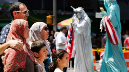 A Muslim family poses for photos, Sunday, July 17, 2016, in New York's Times Square. Behind them are Statue of Liberty characters. (AP Photo/Mark Lennihan)